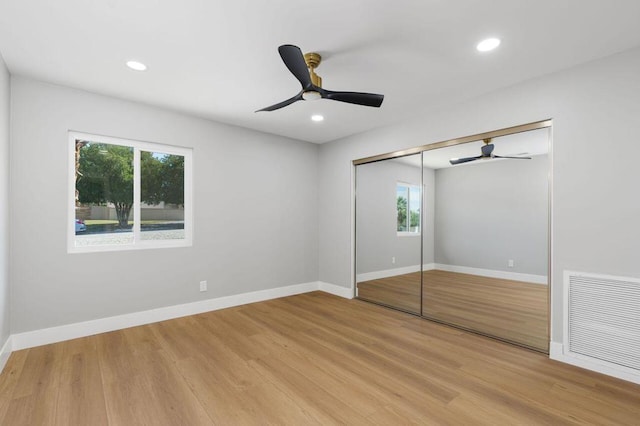 unfurnished bedroom with light hardwood / wood-style flooring, a closet, and ceiling fan