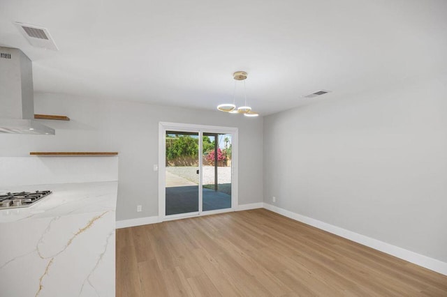 unfurnished dining area with a notable chandelier and light wood-type flooring