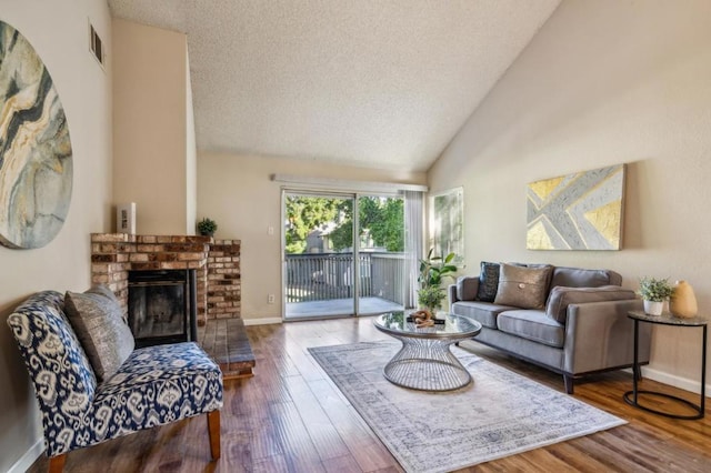 living room with a brick fireplace, wood-type flooring, high vaulted ceiling, and a textured ceiling