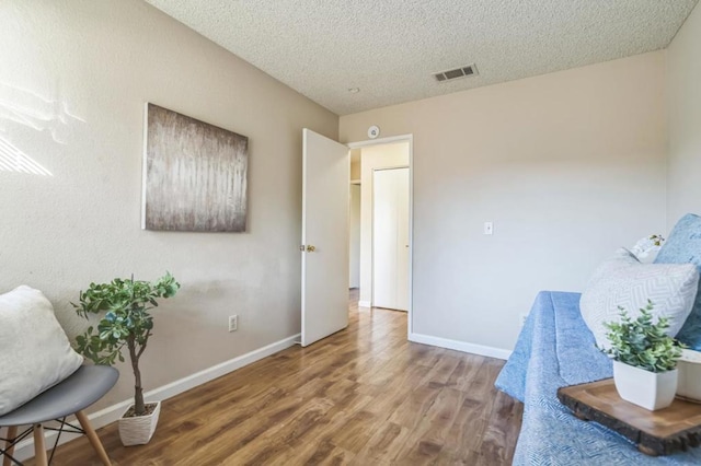 living area with wood-type flooring and a textured ceiling