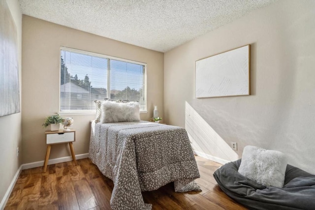 bedroom with dark hardwood / wood-style floors and a textured ceiling