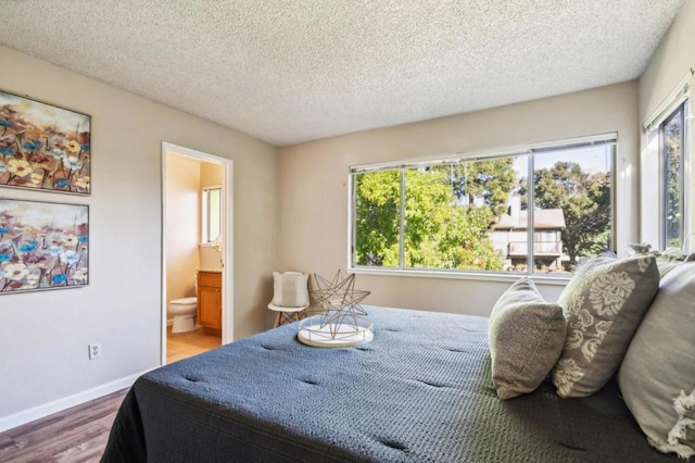 bedroom with wood-type flooring, connected bathroom, and a textured ceiling