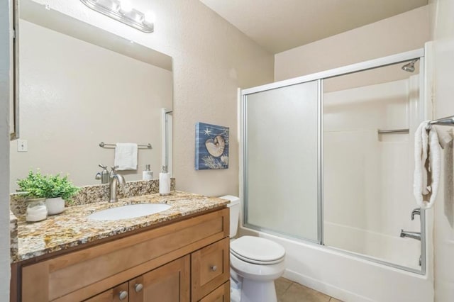 full bathroom featuring vanity, toilet, tile patterned flooring, and combined bath / shower with glass door