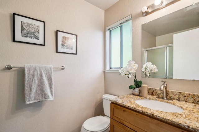 bathroom featuring vanity, toilet, and a shower with door