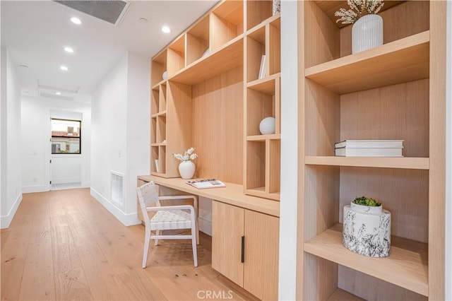 unfurnished office featuring built in desk and light wood-type flooring