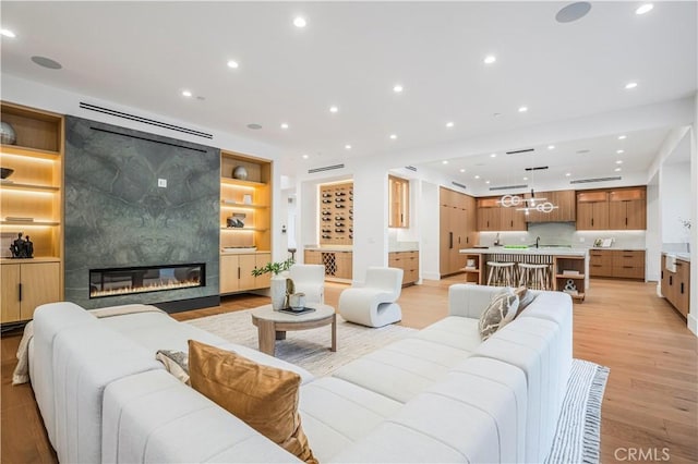 living room featuring built in shelves, a large fireplace, and light hardwood / wood-style floors