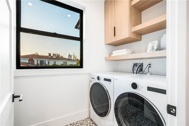 clothes washing area featuring washing machine and dryer, tile patterned flooring, and cabinets