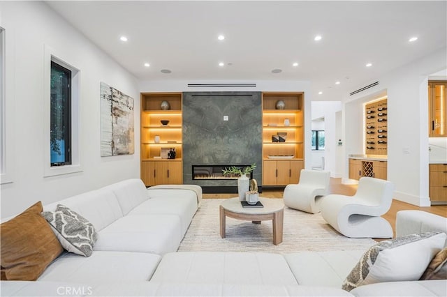 living room with built in shelves, a fireplace, and light hardwood / wood-style flooring