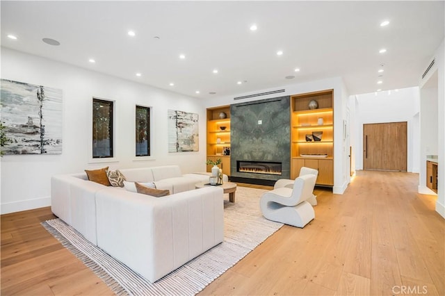 living room featuring built in features, light hardwood / wood-style flooring, and a fireplace