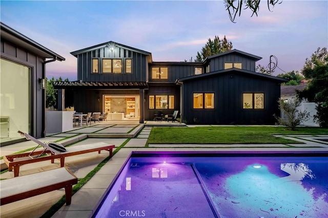 back house at dusk featuring a lawn, a patio area, and an outdoor bar