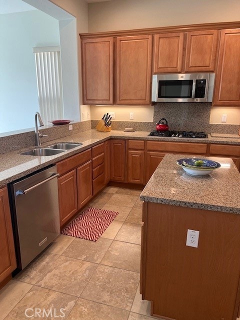 kitchen with appliances with stainless steel finishes, decorative backsplash, light stone countertops, and sink