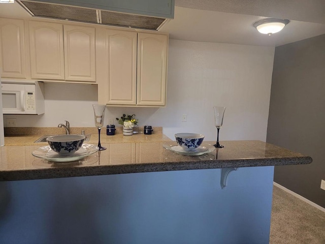 kitchen with sink, kitchen peninsula, carpet flooring, and a breakfast bar