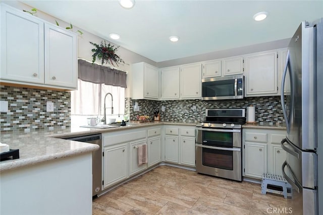 kitchen with decorative backsplash, appliances with stainless steel finishes, white cabinetry, and sink