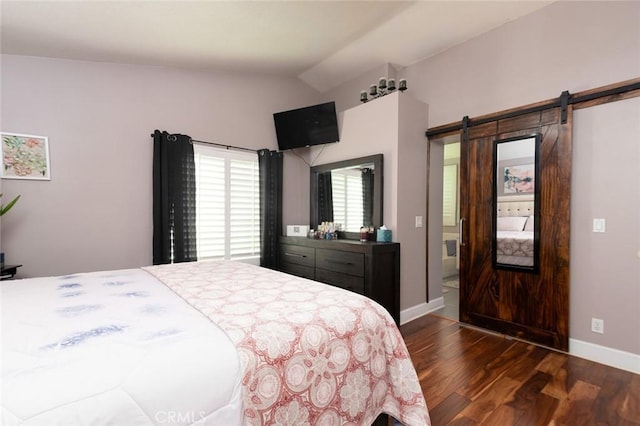 bedroom with a barn door, dark wood-type flooring, and vaulted ceiling