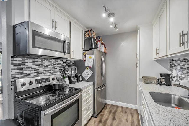 kitchen with white cabinetry, sink, light stone counters, and appliances with stainless steel finishes