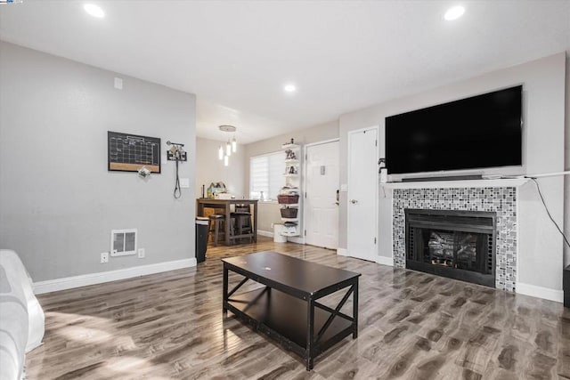 living room featuring hardwood / wood-style flooring, an inviting chandelier, and a tiled fireplace