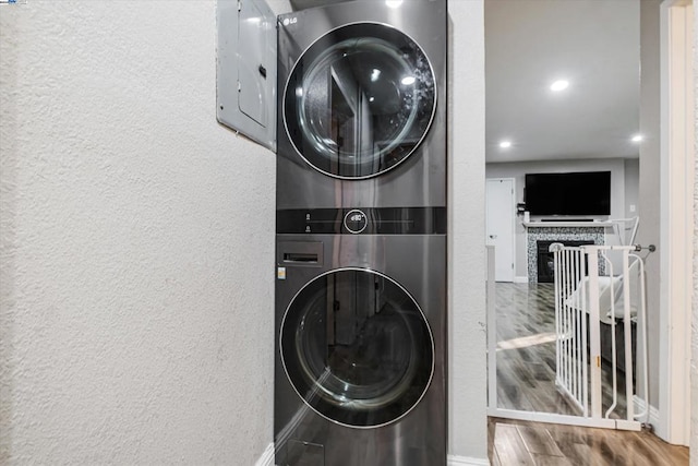 clothes washing area with stacked washer / dryer and hardwood / wood-style flooring