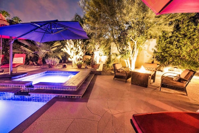 pool at dusk featuring an in ground hot tub, a patio area, and an outdoor fire pit