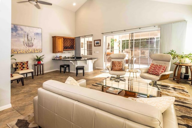 living room with ceiling fan, indoor bar, and high vaulted ceiling