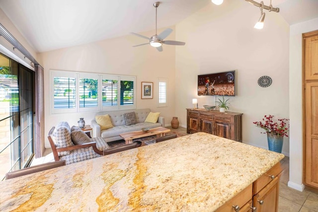 interior space with ceiling fan, light stone countertops, light tile patterned floors, and high vaulted ceiling