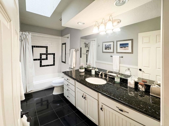 full bathroom featuring toilet, a skylight, shower / bathtub combination with curtain, tile patterned floors, and vanity