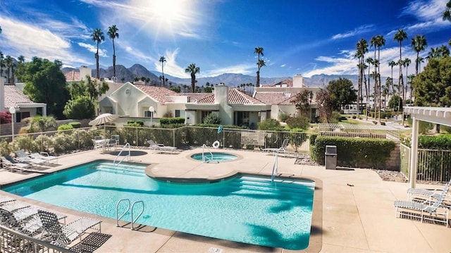 view of swimming pool featuring a hot tub, a mountain view, and a patio