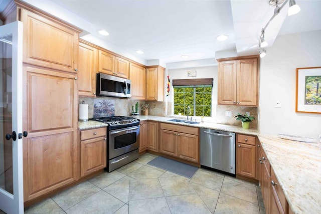 kitchen with tasteful backsplash, appliances with stainless steel finishes, sink, and light stone counters