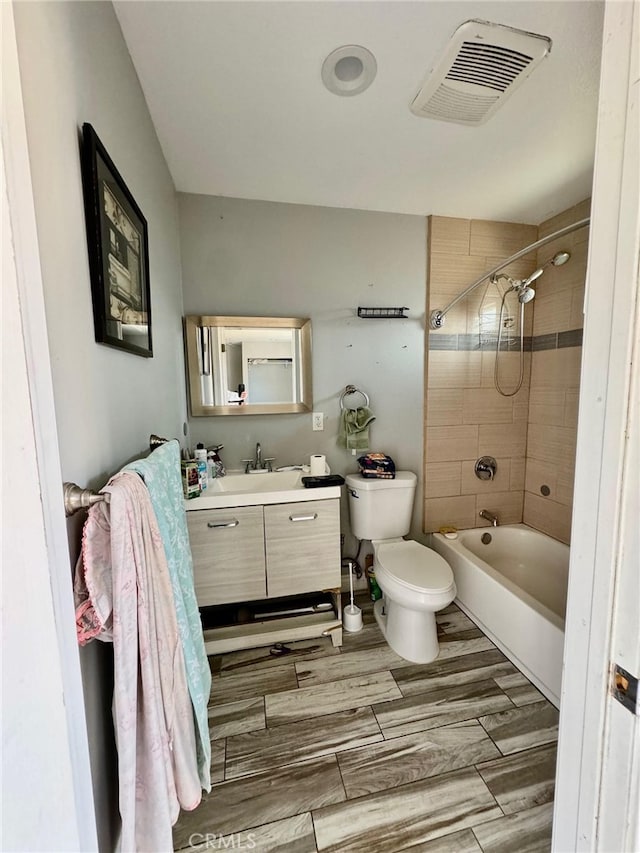 full bathroom with tiled shower / bath, vanity, and toilet