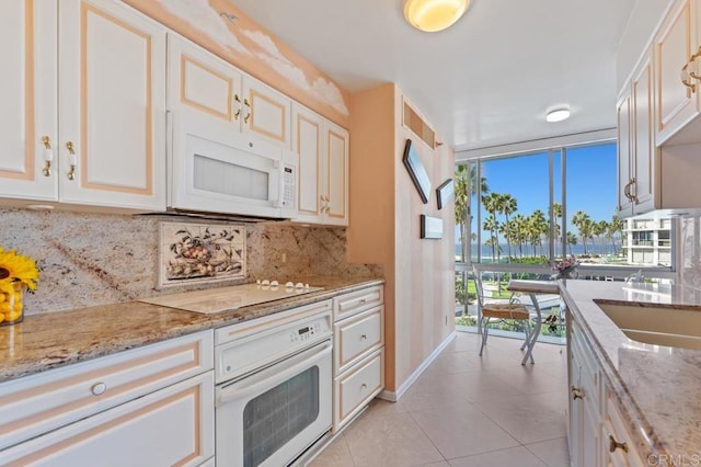 kitchen with white appliances, light stone counters, tasteful backsplash, and light tile patterned flooring