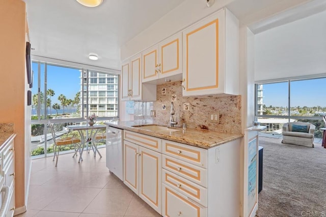 kitchen with decorative backsplash, light carpet, white dishwasher, sink, and light stone counters