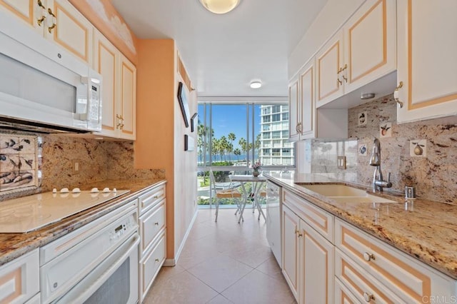 kitchen with sink, light stone countertops, light tile patterned floors, white appliances, and tasteful backsplash