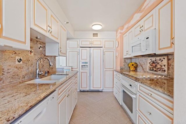 kitchen with white appliances, light stone countertops, sink, white cabinetry, and light tile patterned floors