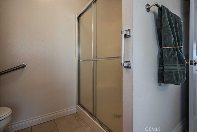 bathroom featuring toilet, tile patterned floors, and a shower with shower door