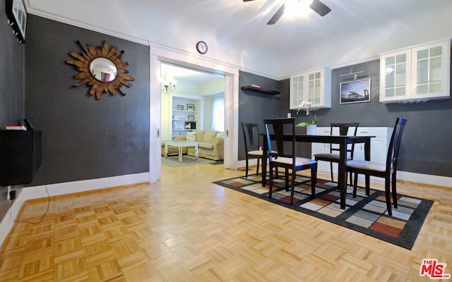 dining space featuring built in shelves, ceiling fan, crown molding, and light parquet flooring