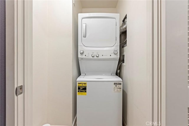 clothes washing area with stacked washer / dryer