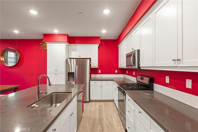 kitchen with white cabinets, stainless steel appliances, light hardwood / wood-style floors, and sink