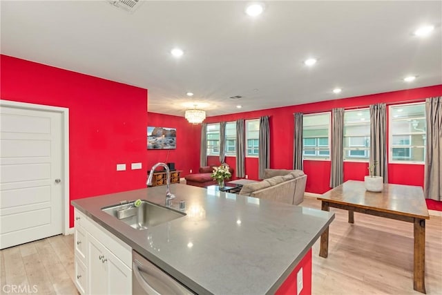 kitchen featuring sink, light hardwood / wood-style flooring, stainless steel dishwasher, a center island with sink, and white cabinets