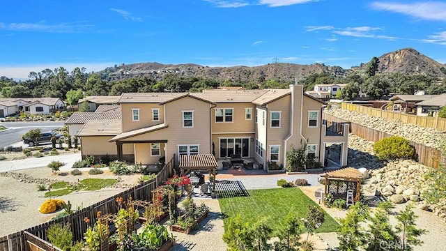 rear view of property featuring a lawn, a mountain view, and a patio