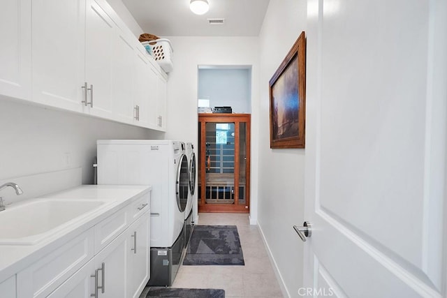 laundry area with separate washer and dryer, sink, light tile patterned floors, and cabinets