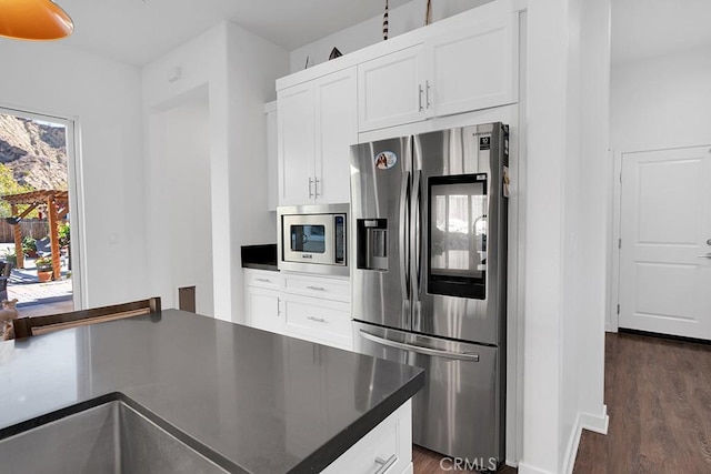 kitchen featuring stainless steel appliances, white cabinetry, dark wood-type flooring, and sink