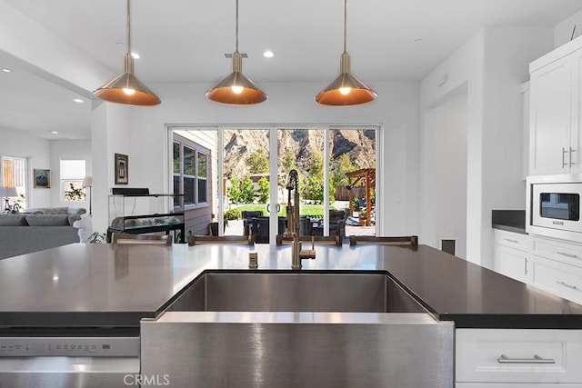 kitchen featuring white cabinets, decorative light fixtures, sink, and white microwave