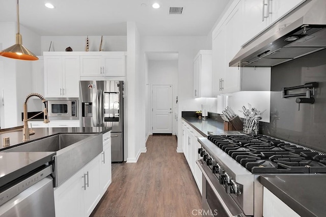 kitchen featuring dark wood-type flooring, sink, appliances with stainless steel finishes, decorative light fixtures, and white cabinetry