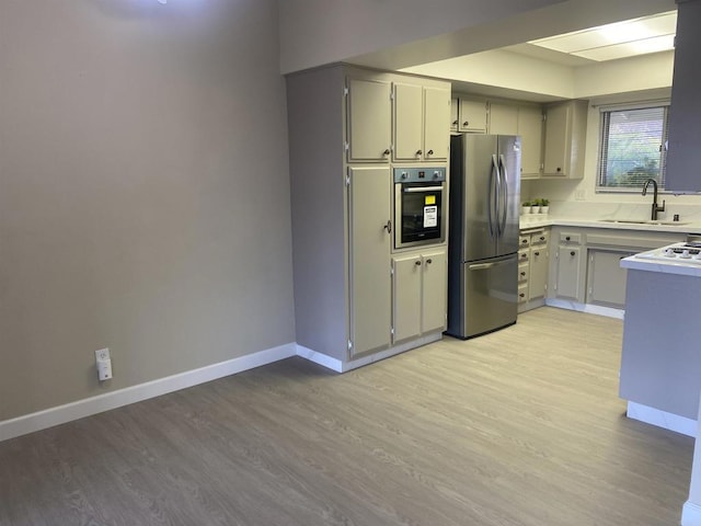 kitchen featuring appliances with stainless steel finishes, sink, gray cabinetry, and light hardwood / wood-style floors