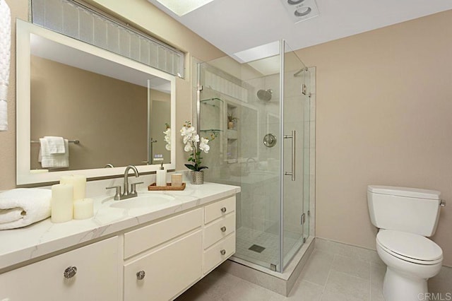 bathroom with tile patterned floors, vanity, toilet, and a shower with door