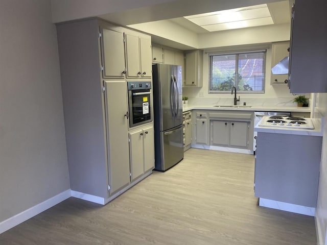 kitchen featuring appliances with stainless steel finishes, sink, and light hardwood / wood-style flooring