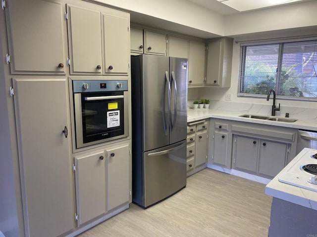 kitchen featuring gray cabinets, appliances with stainless steel finishes, sink, and light hardwood / wood-style flooring