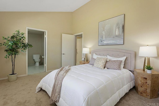 carpeted bedroom with lofted ceiling, ensuite bath, and baseboards