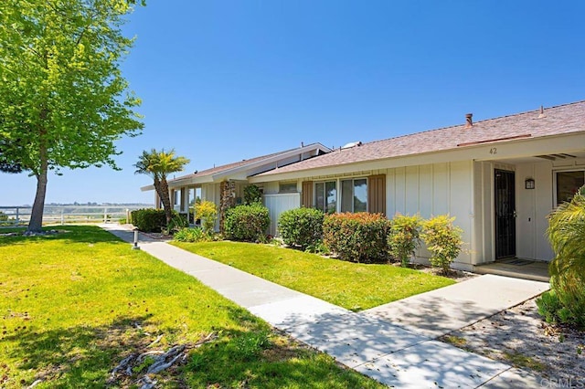 view of front of property featuring fence, a front lawn, and board and batten siding