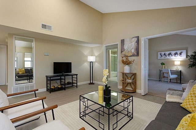 living area with high vaulted ceiling, baseboards, and visible vents