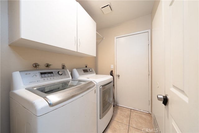 laundry room featuring light tile patterned floors, cabinets, and separate washer and dryer